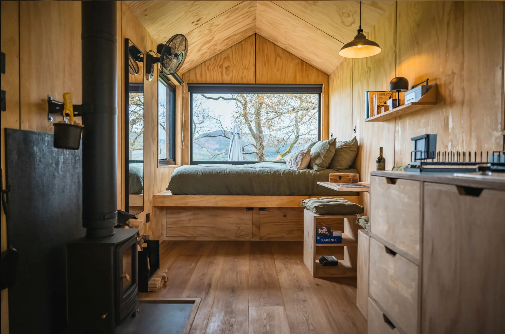 Inside a Shacks cabin, timber-lined walls, a window seat and a wood-burning stove