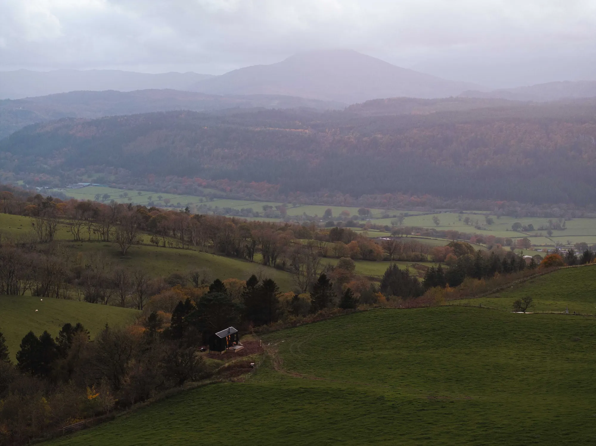 Aerial view of a Draco cabin set in rolling green farmland and hedgerows
