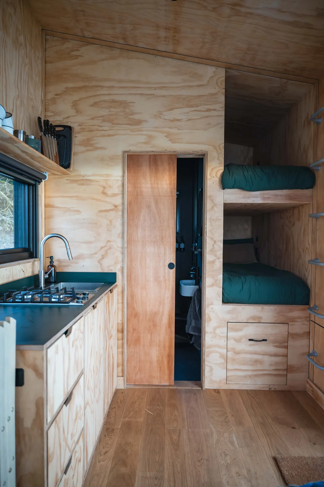 Inside the Phoenix family cabin: kitchen alongside built-in bunk beds in warm timber