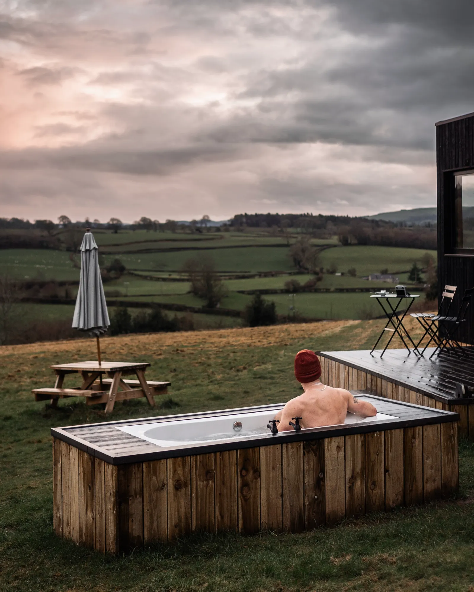 A guest in the outdoor hot tub beside the Phoenix cabin, looking over the valley