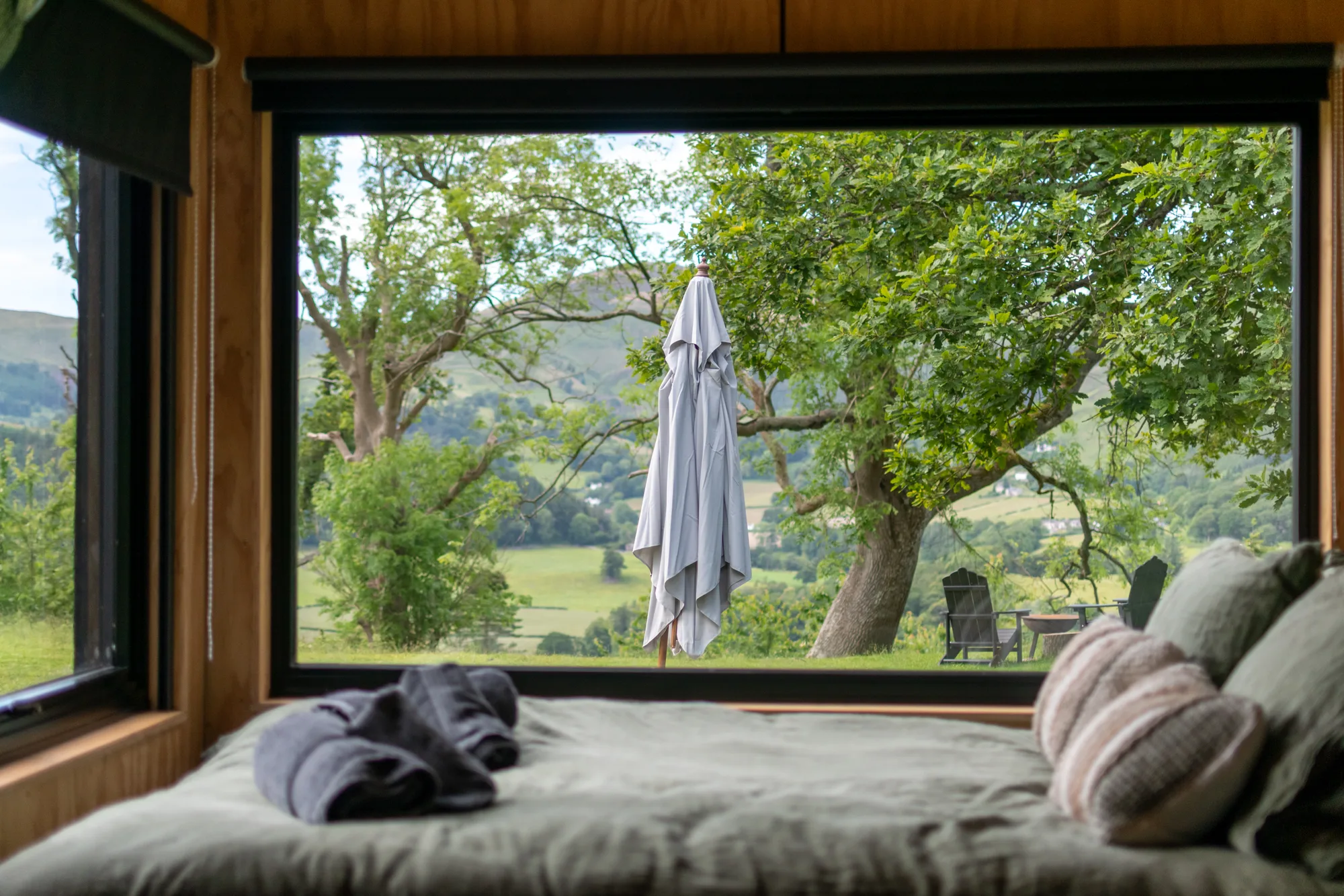 Looking out from the cabin bed through a picture window onto trees and pasture