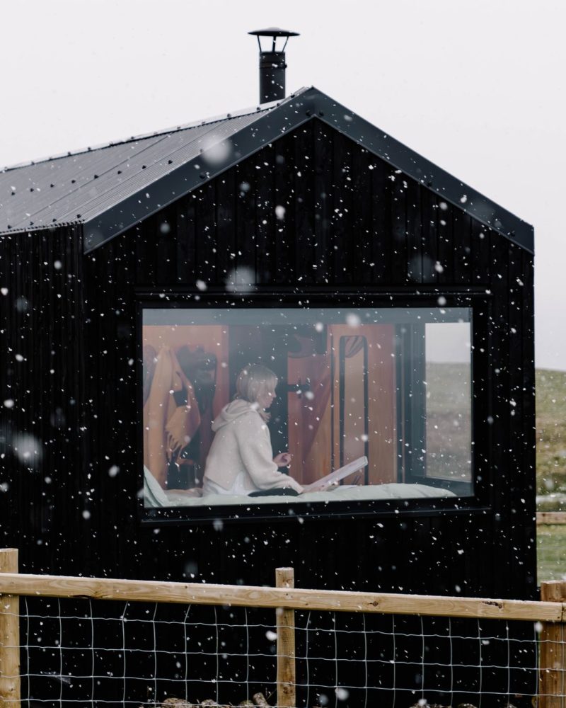 a guest staying in an off-grid cabin with snow falling outside.